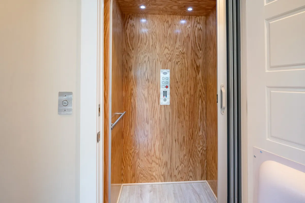 A crisp interior shot of the elevator and its modern, wood-paneled foyer, showcasing clean lines and contemporary lighting fixtures. The setup clearly communicates ease of movement between floors.