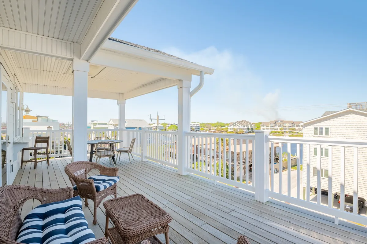 An outdoor deck with wicker chairs arranged for socializing or quiet relaxation, overlooking the tranquil surroundings. The deck's position suggests a scenic vantage point ideal for sunset watching and unwinding after a day of adventure.