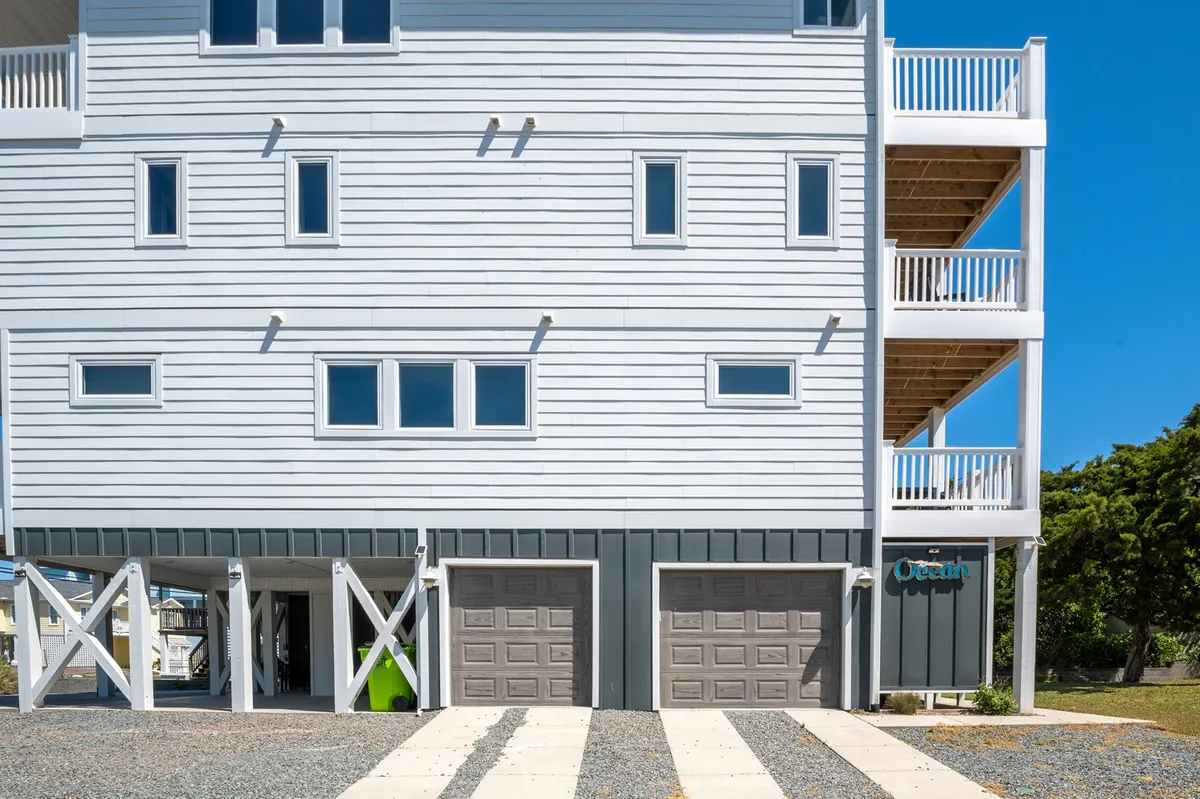 The three-story Dietrich Beach House stands tall with multiple balconies and a garage, exuding a welcoming, modern beach house vibe. The exterior highlights private outdoor spaces ideal for enjoying the coastal views and fresh air.