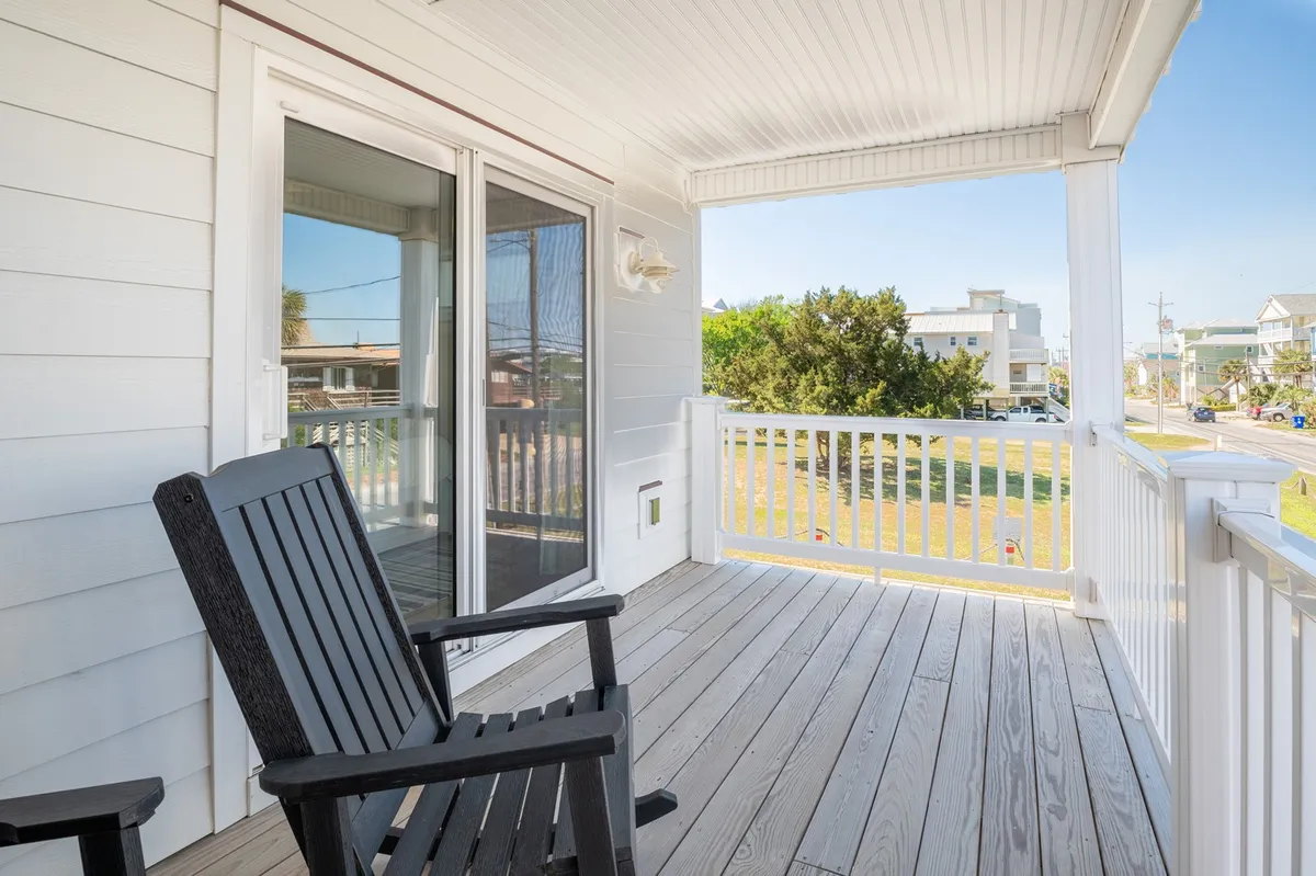 A tranquil balcony scene featuring a black wooden rocking chair, ample space for gatherings, and a sweeping view of the surrounding area—ideal for morning coffee, sunset watching, or relaxing in quieter seasons.