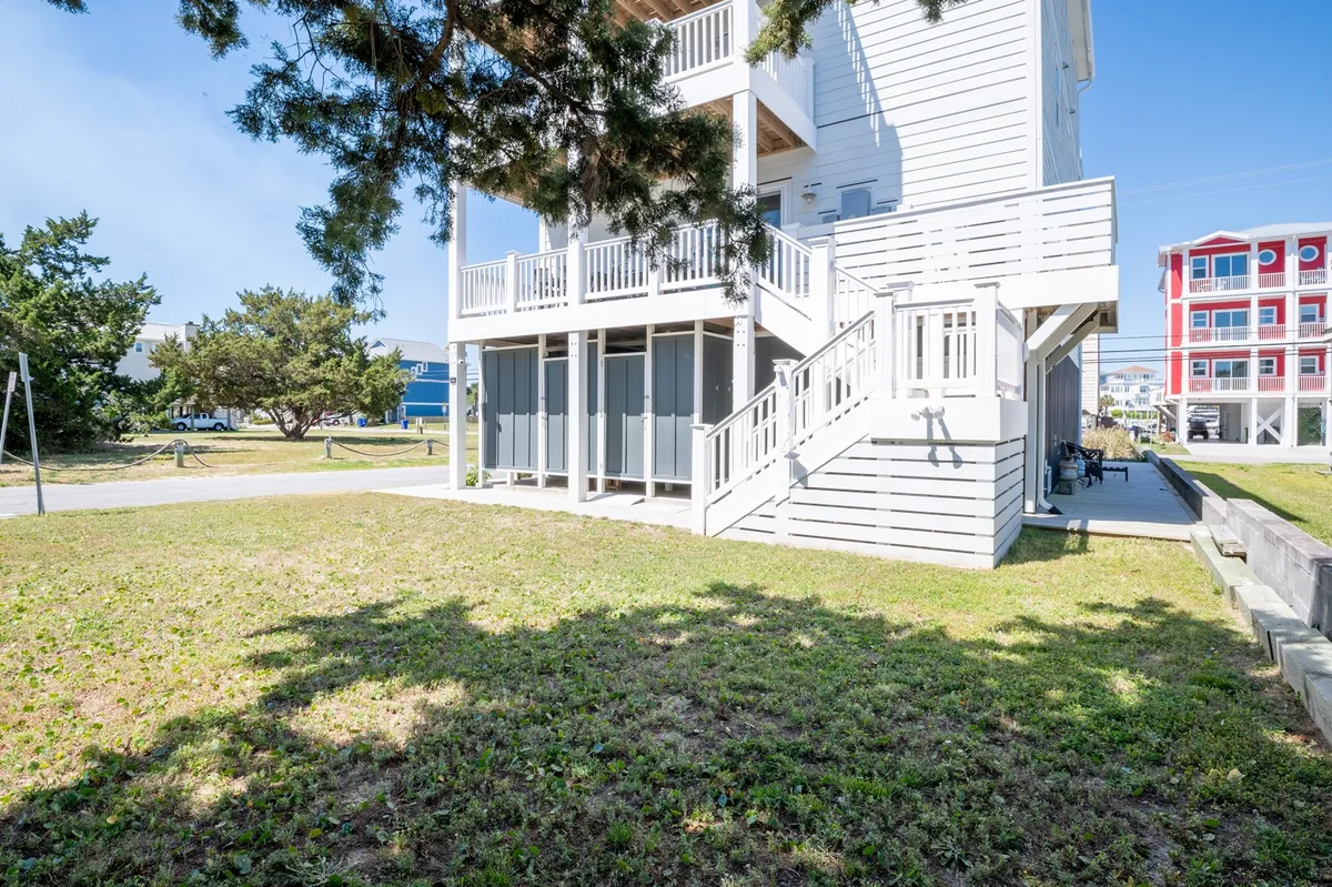 This exterior image features a spacious two-story deck overlooking a grassy, fenced backyard. The image captures both the deck and the yard, showing areas for outdoor dining, play, and relaxation, along with open access to the outdoor space.